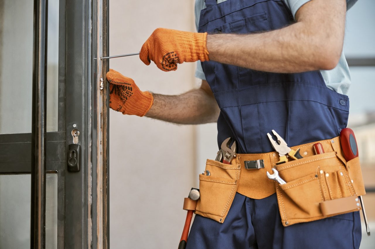 male hands in gloves repairing door in house
